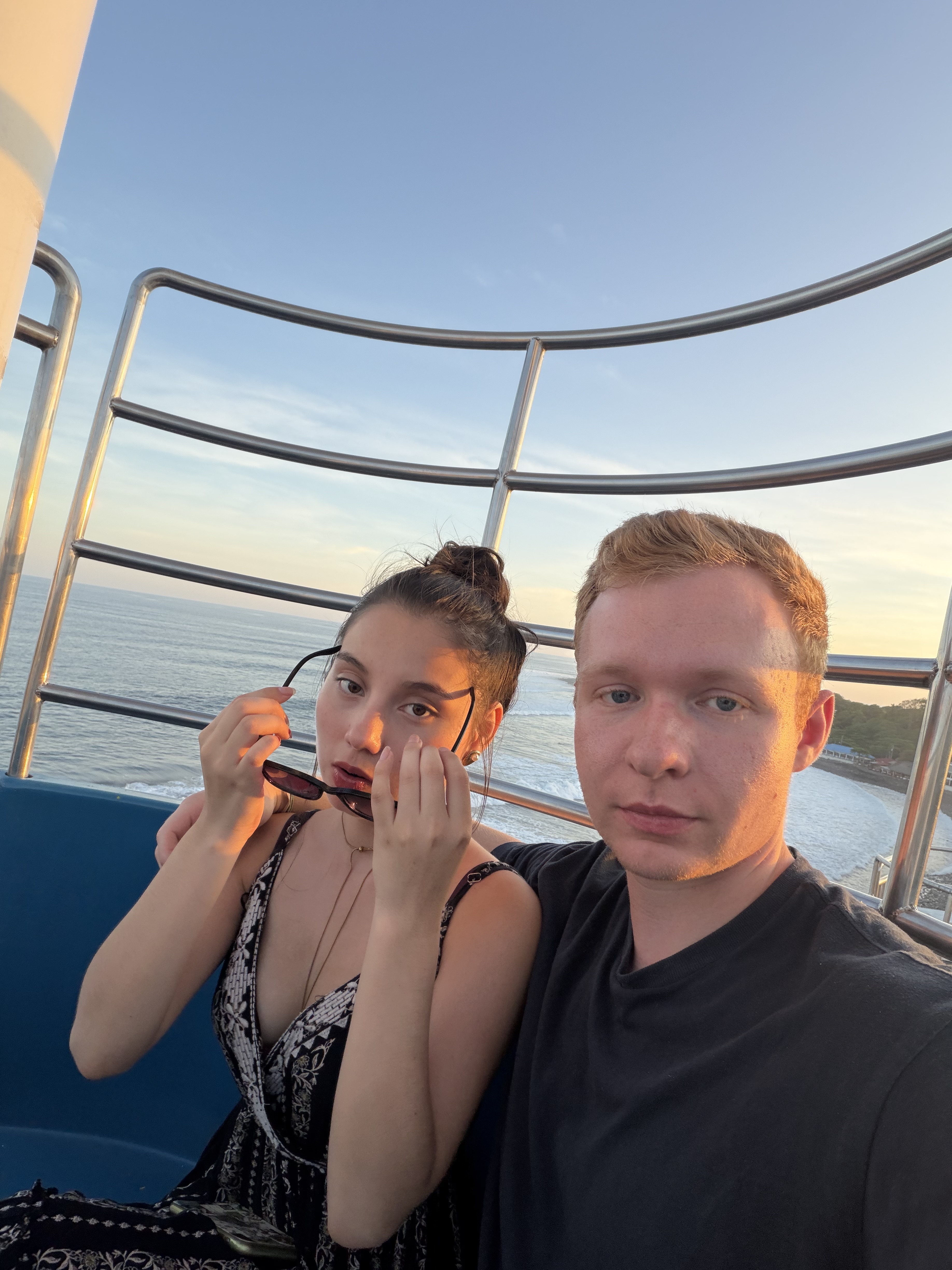 A couple selfie on a cruise deck at sunset with the ocean behind